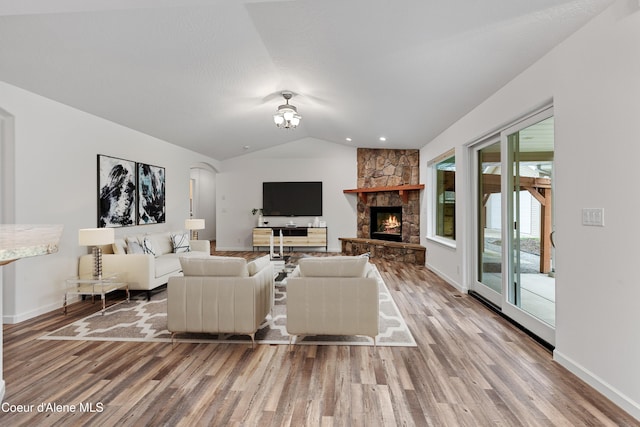 5519 N Wade St, Coeur Dalene, ID 83815 - living area with wood finished floors, lofted ceiling, a stone fireplace, arched walkways, and baseboards