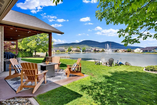 14097 N Pristine Cir, Rathdrum, ID 83858 - view of green lawn featuring a fire pit, a water and mountain view, and a patio