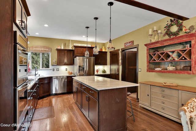17940 W Sheltered Ct, Hauser, ID 83854 - kitchen featuring appliances with stainless steel finishes, hardwood / wood-style flooring, a kitchen island, open shelves, and a sink