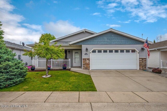 13458 N Bighorn Canyon St, Rathdrum, ID 83858 - view of front facade featuring stone siding, a garage, driveway, a porch, and a front yard