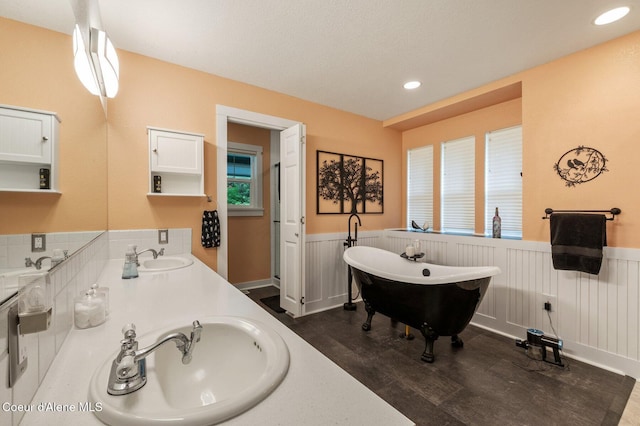 bathroom featuring a wainscoted wall, a freestanding bath, double vanity, wood finished floors, and recessed lighting