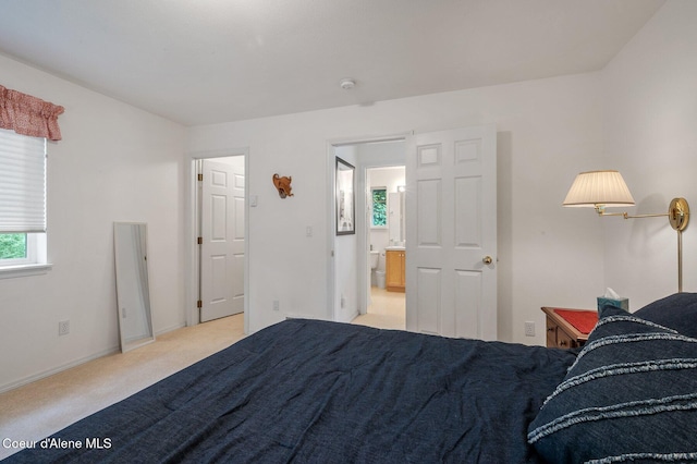 bedroom with light carpet, baseboards, and ensuite bathroom