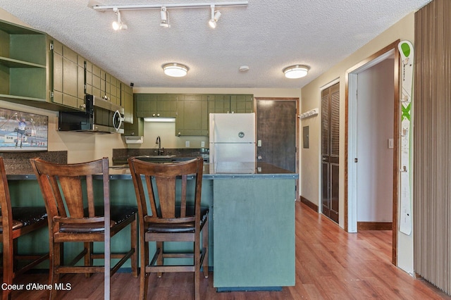 495 NW Psge # 103, Sandpoint, ID 83864 - kitchen featuring freestanding refrigerator, green cabinets, dark countertops, a sink, and a peninsula