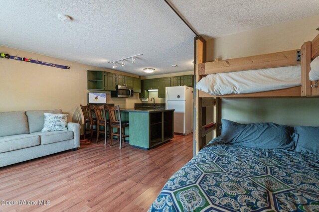 495 NW Psge # 103, Sandpoint, ID 83864 - bedroom with freestanding refrigerator, a textured ceiling, light wood-type flooring, track lighting, and a sink