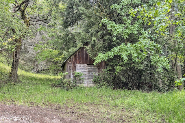 view of yard with a detached garage, an outbuilding, and a forest view