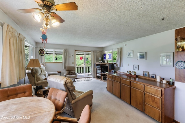 living room with a textured ceiling, healthy amount of natural light, light colored carpet, and ceiling fan