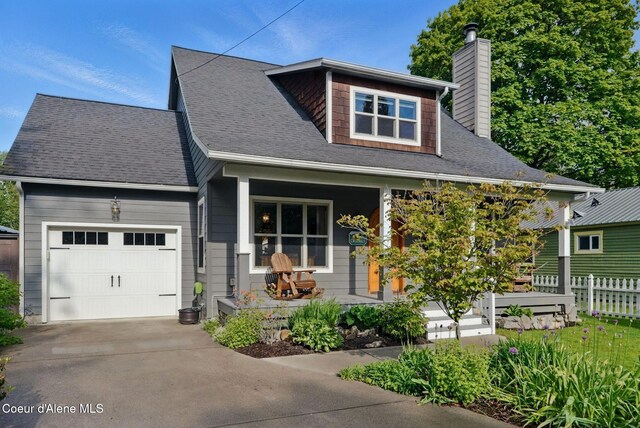 619 N Florence Ave, Sandpoint, ID 83864 - view of front of house featuring a porch, a chimney, an attached garage, driveway, and fence