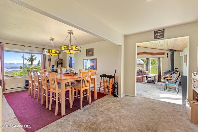 dining area with a wood stove and carpet floors