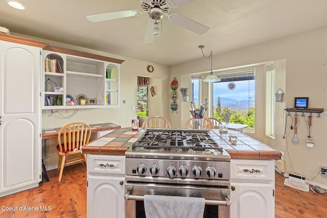 kitchen with high end stove, tile countertops, and white cabinets