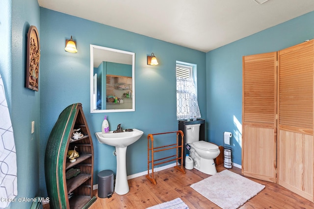 bathroom featuring wood finished floors, toilet, baseboards, and a sink