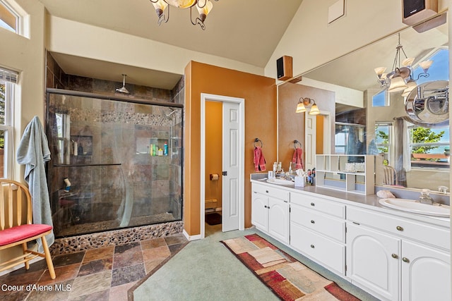 bathroom featuring a shower stall, plenty of natural light, double vanity, vaulted ceiling, and baseboards