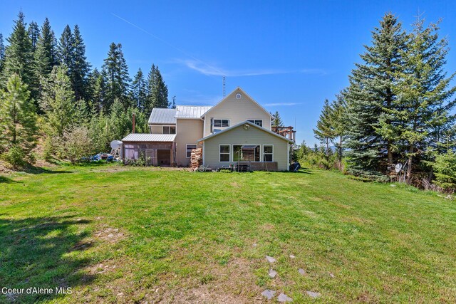 rear view of property featuring a yard and metal roof