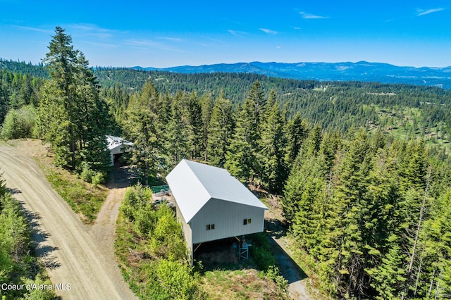 view of subject property featuring a heavily wooded area and a mountain backdrop
