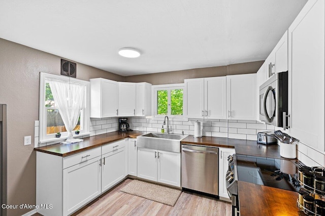 908 E Coeur D Alene Ave, Coeur Dalene, ID 83814 - kitchen featuring appliances with stainless steel finishes, a sink, butcher block counters, backsplash, and light wood finished floors