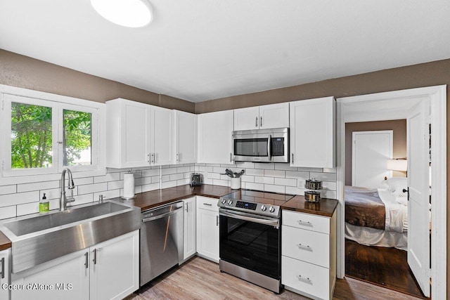 908 E Coeur D Alene Ave, Coeur Dalene, ID 83814 - kitchen with stainless steel appliances, decorative backsplash, white cabinetry, a sink, and light wood-style floors