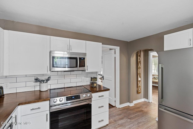 908 E Coeur D Alene Ave, Coeur Dalene, ID 83814 - kitchen featuring appliances with stainless steel finishes, wooden counters, arched walkways, backsplash, and light wood finished floors