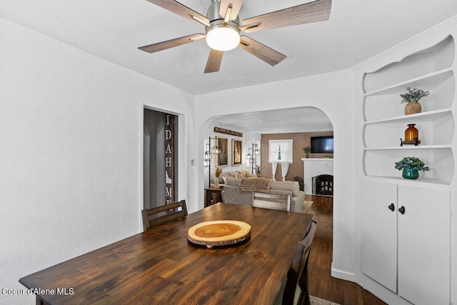 908 E Coeur D Alene Ave, Coeur Dalene, ID 83814 - dining area featuring arched walkways, a ceiling fan, wood finished floors, a fireplace, and a textured wall