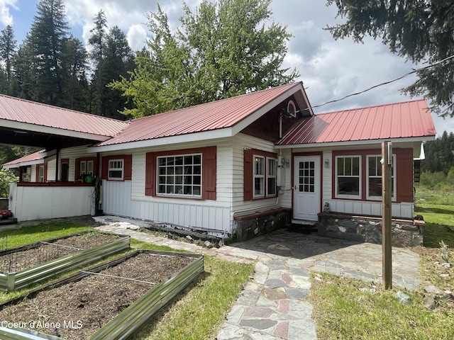 84 Highland Flats Rd, Naples, ID 83847 - view of front of house featuring a vegetable garden, metal roof, and a patio area