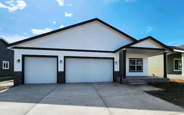2941 N Wrenley Ln, Post Falls, ID 83854 - view of front facade with a garage, concrete driveway, stone siding, and a porch