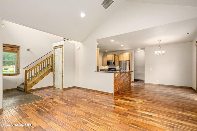 15360 N Nixon Loop, Rathdrum, ID 83858 - unfurnished living room with a chandelier, light wood-style floors, high vaulted ceiling, stairway, and baseboards