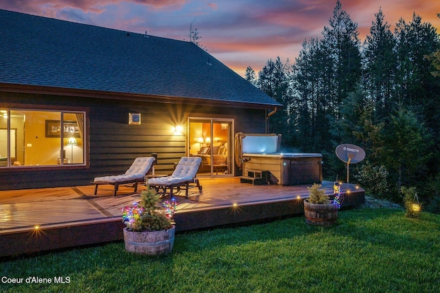 29264 N Ramsey Rd, Athol, ID 83801 - back of property at dusk featuring a hot tub, a wooden deck, a shingled roof, and a lawn