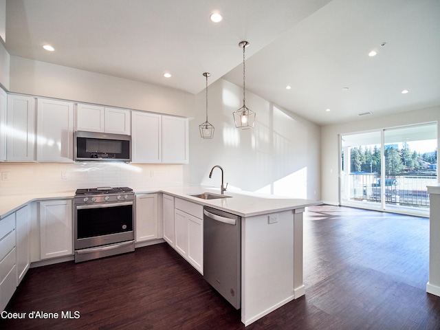 898 E Railroad Ave, Post Falls, ID 83854 - kitchen featuring stainless steel appliances, a sink, a peninsula, backsplash, and dark wood-style flooring