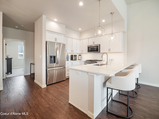 898 E Railroad Ave, Post Falls, ID 83854 - kitchen featuring stainless steel appliances, a peninsula, a sink, dark wood finished floors, and white cabinets