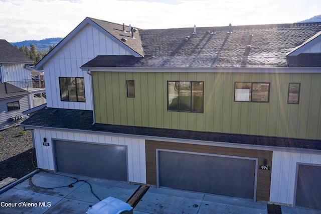 898 E Railroad Ave, Post Falls, ID 83854 - view of side of property featuring a shingled roof, an attached garage, concrete driveway, a mountain view, and board and batten siding