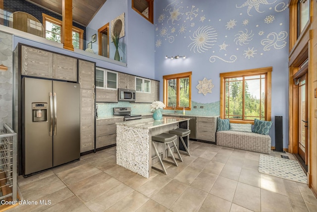 23 S Lightning Spur Ln, Coeur Dalene, ID 83814 - kitchen with stainless steel appliances, high vaulted ceiling, a center island, a breakfast bar area, and light tile patterned floors