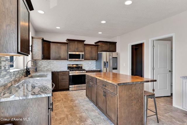 6314 Irish Dr, Rathdrum, ID 83858 - kitchen with appliances with stainless steel finishes, a sink, tasteful backsplash, dark brown cabinets, and recessed lighting