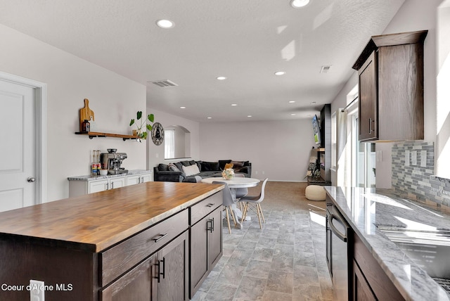 6314 Irish Dr, Rathdrum, ID 83858 - kitchen featuring butcher block counters, open floor plan, arched walkways, recessed lighting, and tasteful backsplash