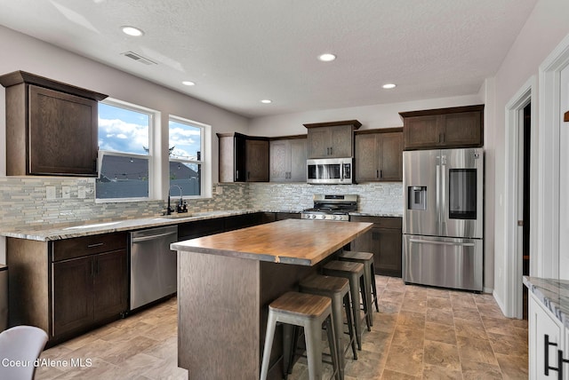 6314 Irish Dr, Rathdrum, ID 83858 - kitchen with stainless steel appliances, dark brown cabinetry, wood counters, backsplash, and a textured ceiling