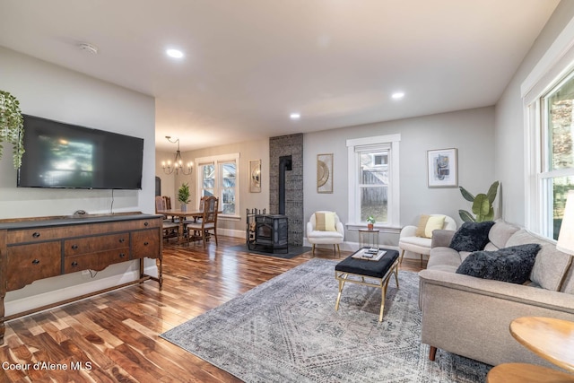 living room with a wood stove, plenty of natural light, wood finished floors, a chandelier, and recessed lighting