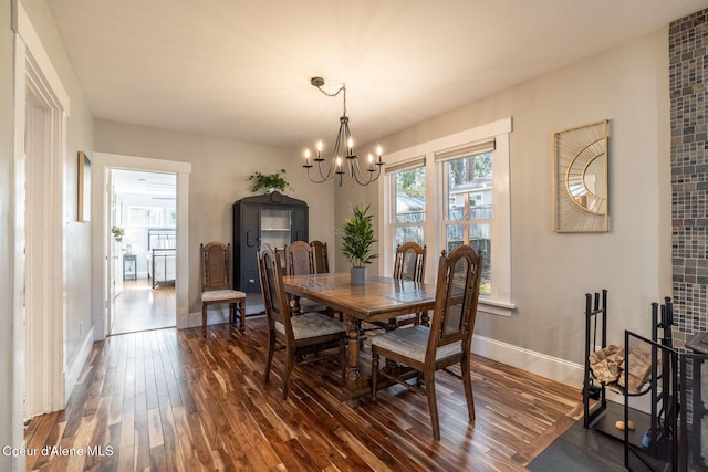 dining area with dark wood finished floors, a chandelier, and baseboards