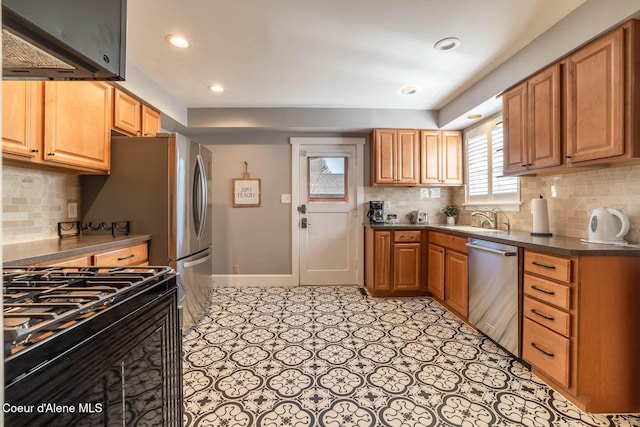 kitchen with stainless steel dishwasher, range with gas cooktop, tasteful backsplash, a sink, and dark countertops