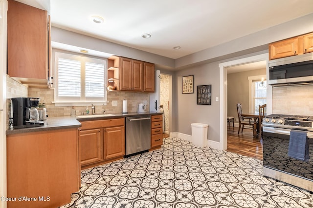 kitchen with stainless steel appliances, a sink, backsplash, open shelves, and dark countertops