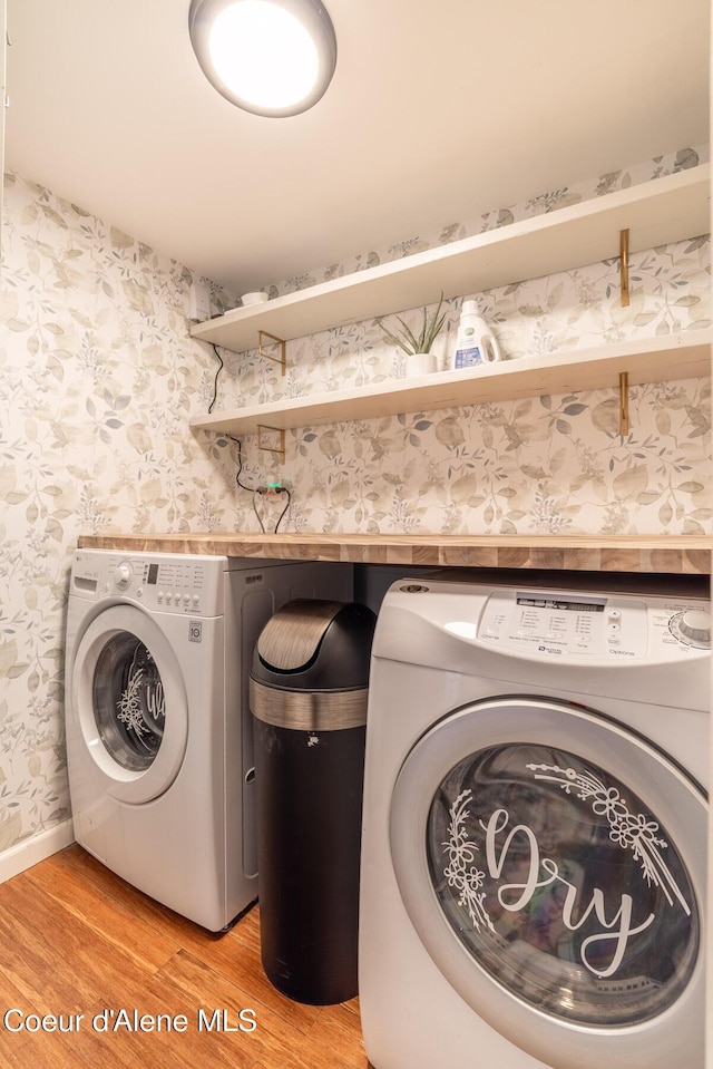 laundry room with light wood-style flooring, wallpapered walls, and separate washer and dryer