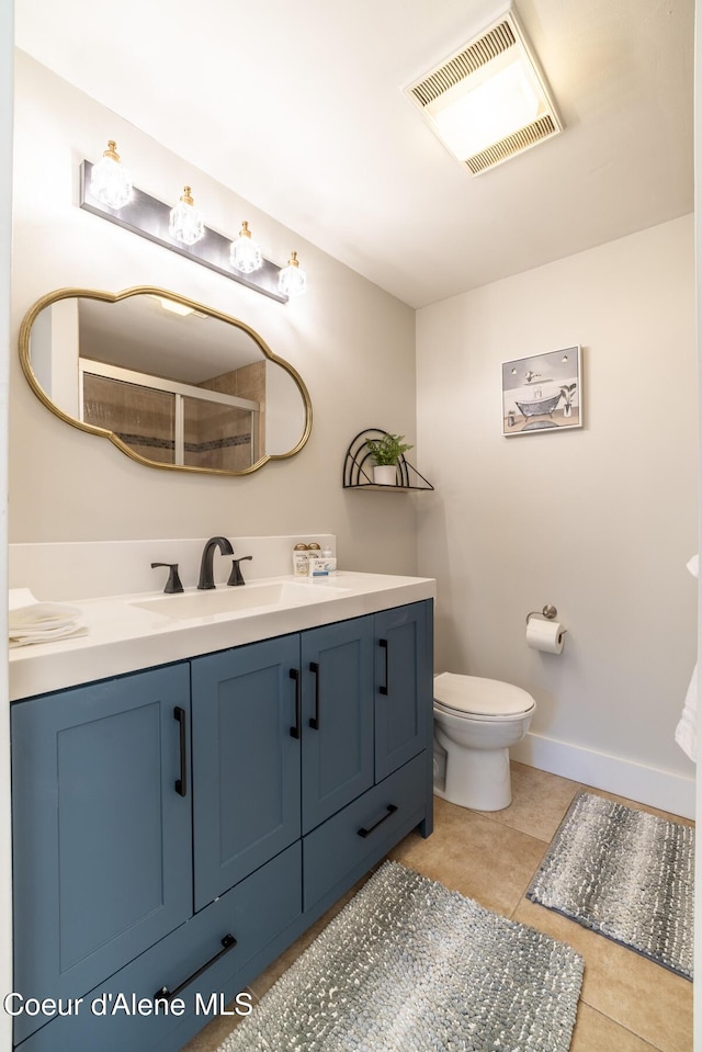 bathroom with vanity, tile patterned floors, a shower with shower door, toilet, and baseboards
