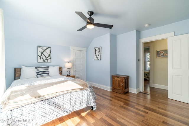 bedroom featuring baseboards, wood finished floors, vaulted ceiling, and a ceiling fan