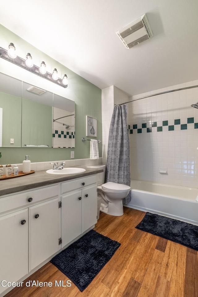 full bathroom featuring toilet, vanity, wood finished floors, and shower / bath combination with curtain