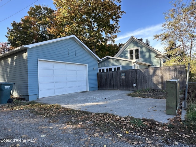 view of front facade featuring fence, driveway, a garage, and an outbuilding