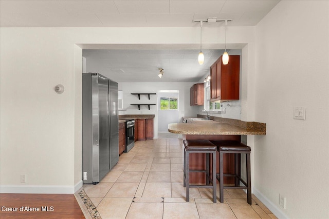 342 Summit Blvd, Priest River, ID 83856 - kitchen with stainless steel appliances, a peninsula, a kitchen breakfast bar, baseboards, and a sink