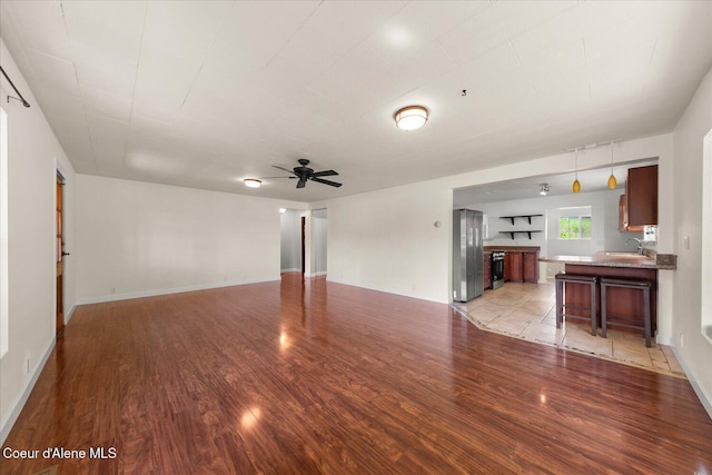 342 Summit Blvd, Priest River, ID 83856 - unfurnished living room featuring light wood-style floors, a sink, a ceiling fan, and baseboards