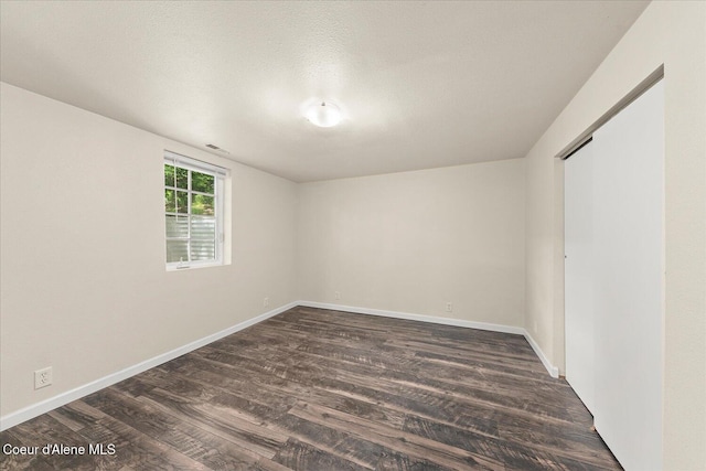 342 Summit Blvd, Priest River, ID 83856 - unfurnished bedroom featuring dark wood-type flooring, baseboards, a textured ceiling, and a closet