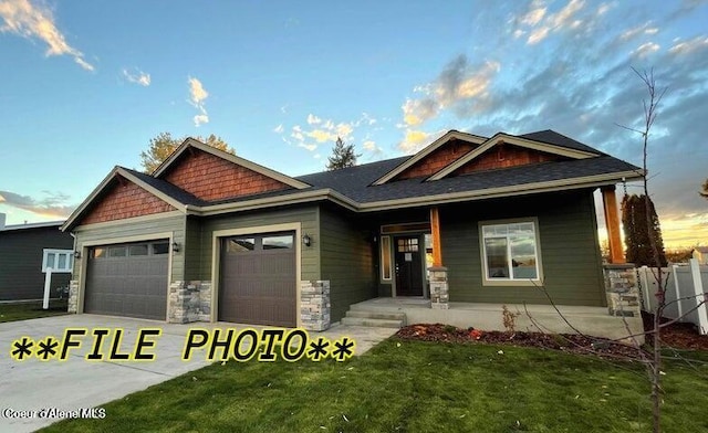 2060 E Plaza Ct, Post Falls, ID 83854 - craftsman house featuring a garage, concrete driveway, a porch, a front yard, and stone siding
