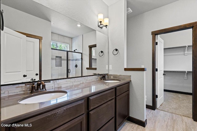 2060 E Plaza Ct, Post Falls, ID 83854 - bathroom with a shower stall, wood finished floors, a spacious closet, double vanity, and baseboards