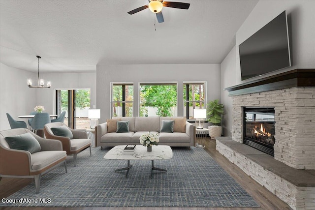 2060 E Plaza Ct, Post Falls, ID 83854 - living room featuring wood finished floors, a chandelier, a ceiling fan, and a stone fireplace