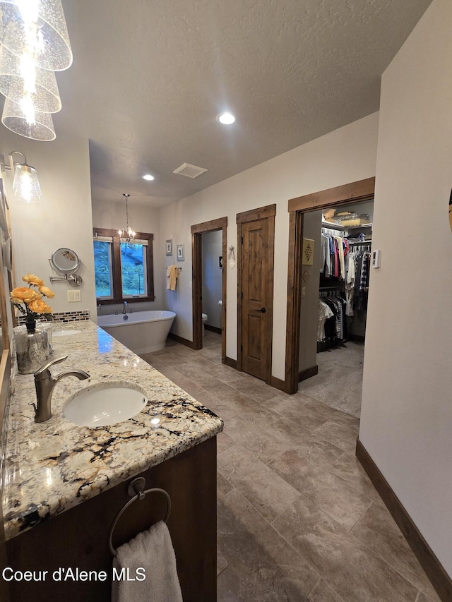 12552 N Walden Loop, Rathdrum, ID 83858 - full bathroom featuring baseboards, a spacious closet, double vanity, recessed lighting, and a chandelier