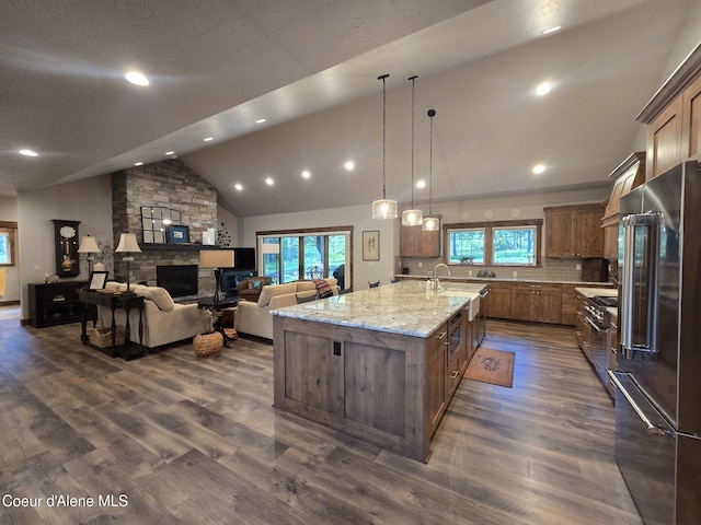 12552 N Walden Loop, Rathdrum, ID 83858 - kitchen featuring high quality appliances, vaulted ceiling, plenty of natural light, a stone fireplace, and a large island with sink