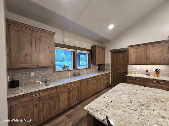 12552 N Walden Loop, Rathdrum, ID 83858 - kitchen with vaulted ceiling, decorative backsplash, dark wood-style floors, and light stone countertops